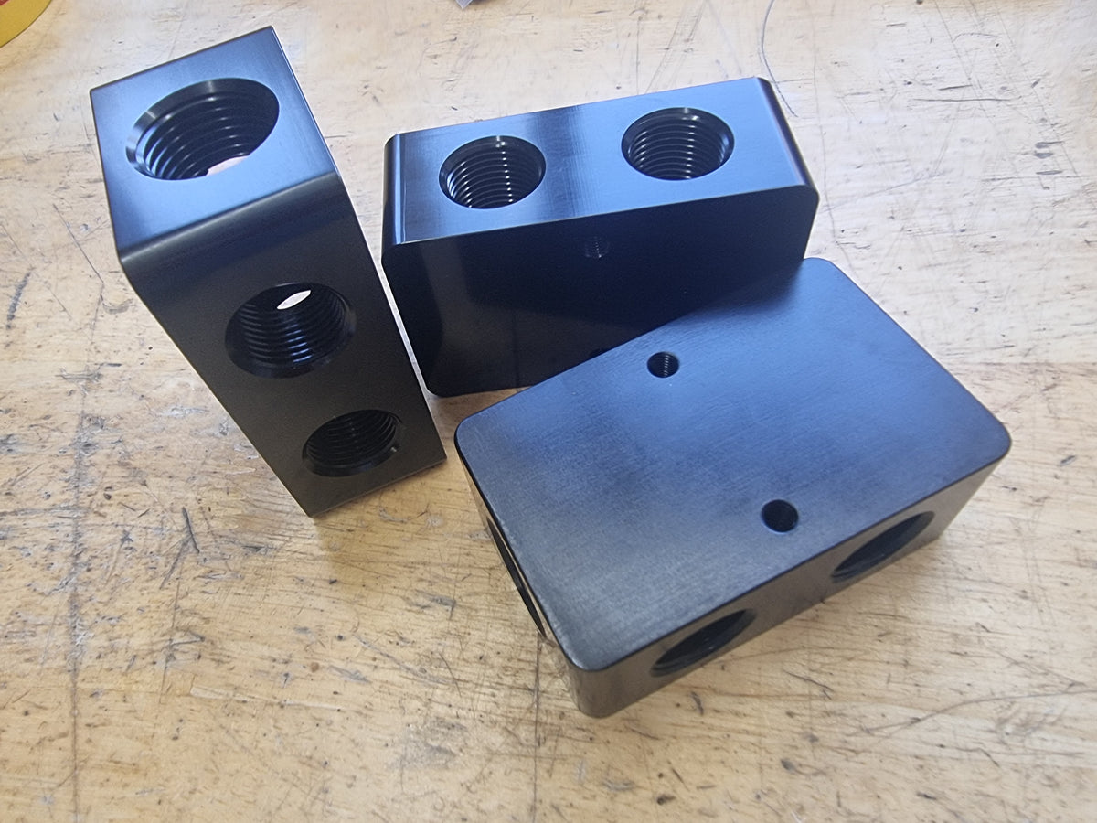 Three AN10 distribution blocks with an anodized black finish. AN10 Distribution Block – Oil, Coolant, Fuel, and Vacuum