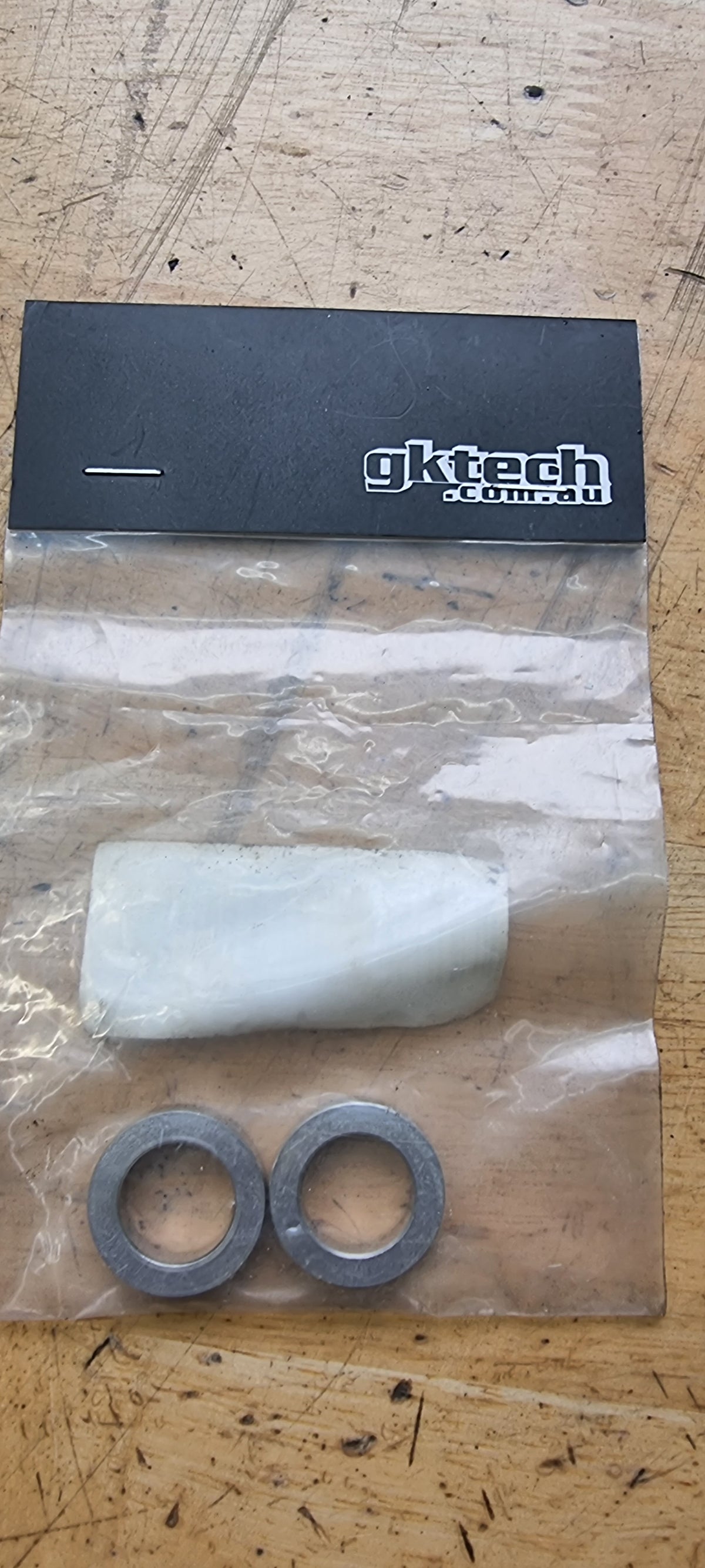GKteck branded steering wheel shim kit, including a white shim and two black washers, packaged in a clear plastic bag.