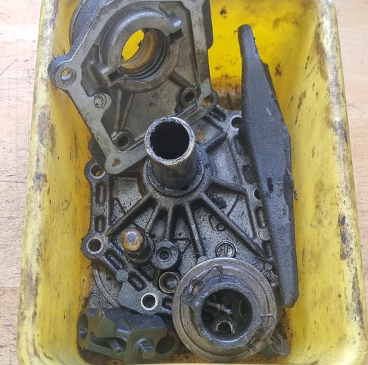 Used RB30 Patrol manual gearbox front-end assembly parts displayed on a yellow surface, including various metallic components.