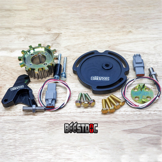 An assortment of black and metallic engine timing synchronization trigger kit components laid out on a wooden surface, including crankshaft timing gear, mounting hardware, and sensor components. skyline oem nissan parts gtr stagea safero r32 r33 r34 rb neo rb25 rb26 rb30