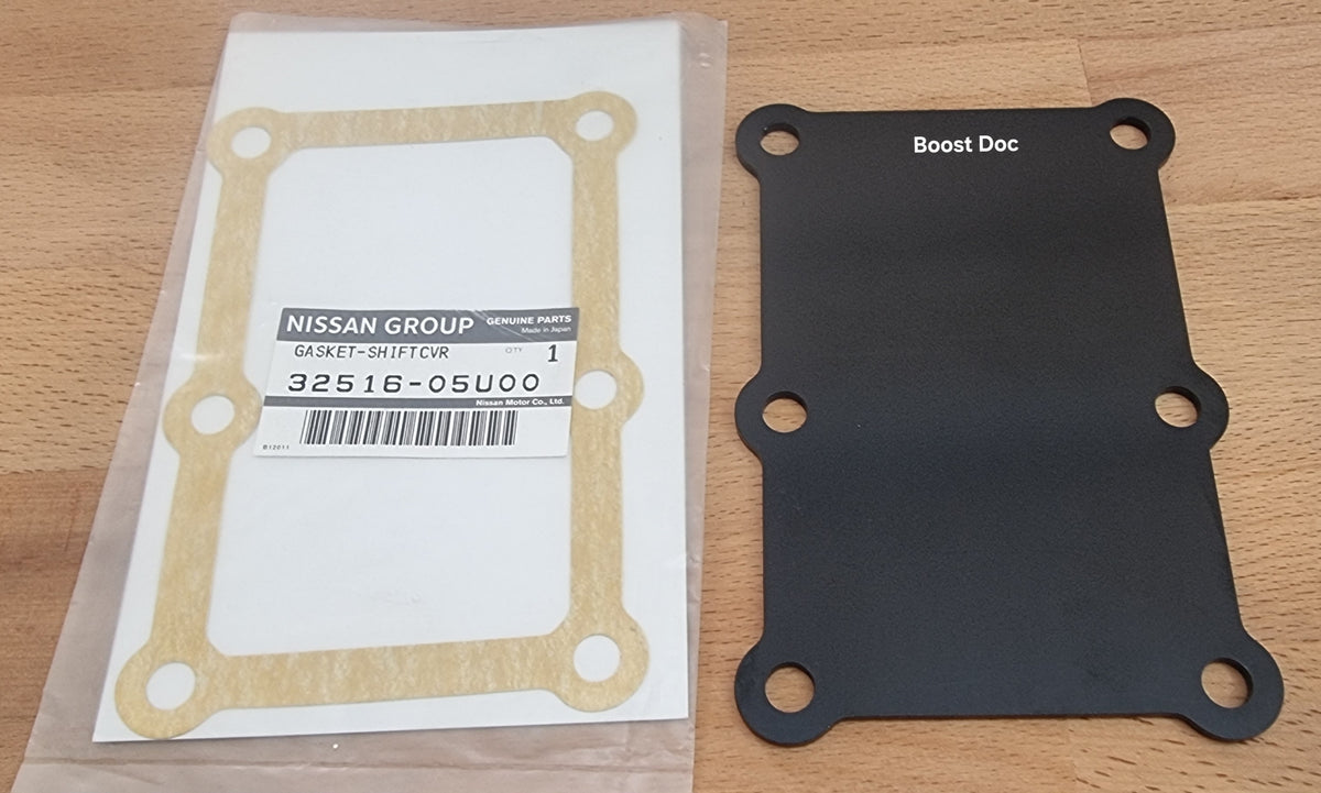 A black metal shifter blanking plate alongside its gasket, packaged in plastic, labeled for Nissan Group with vehicle model compatibility information.