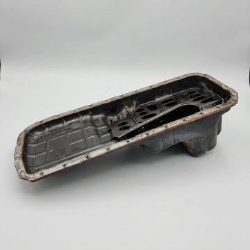 A black deep rear hump oil pan, presumably made of metal, with visible signs of wear and dirt Used RB Deep Rear Hump Oil Pan skyline replacement parts genuine oem nissan part