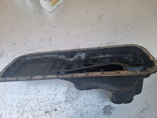 A black deep rear hump oil pan, presumably made of metal, with visible signs of wear and dirt Used RB Deep Rear Hump Oil Pan skyline replacement parts genuine oem nissan part